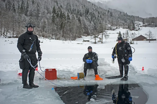 Drei Taucher am Eisloch